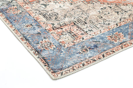 Corner of a patterned rug with blue and pink tones on a white background