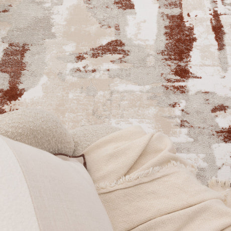 Close-up of a textured rug with a blanket draped over it, featuring neutral colors.