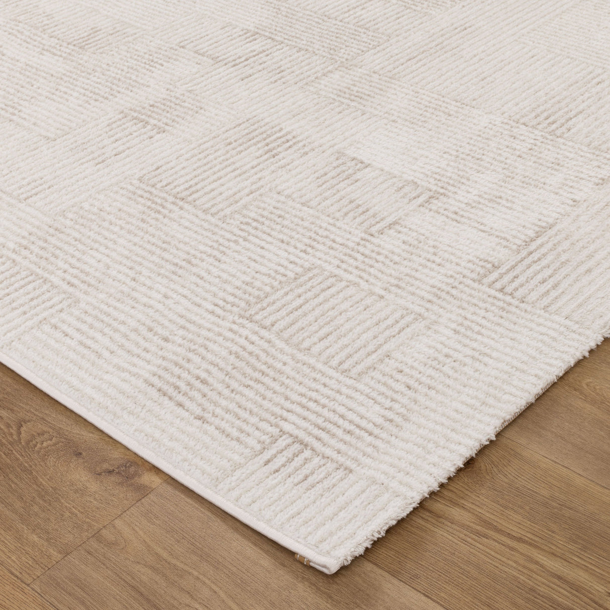 Close-up of a textured white rug on a wooden floor